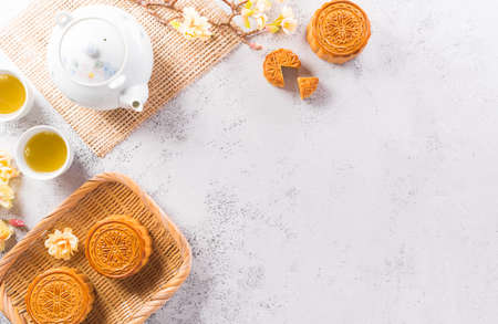 Chinese Mid-Autumn Festival concept made from mooncakes, tea and plum blossom on white stone background.の写真素材