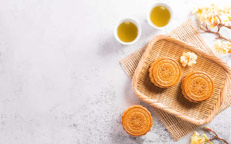 Chinese Mid-Autumn Festival concept made from mooncakes, tea and plum blossom on white stone background.の写真素材
