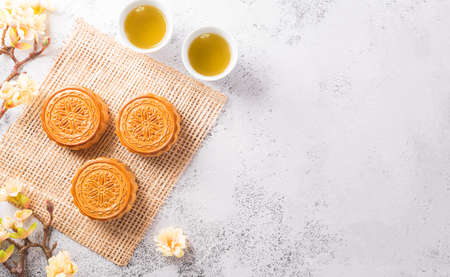 Chinese Mid-Autumn Festival concept made from mooncakes, tea and plum blossom on white stone background.の写真素材