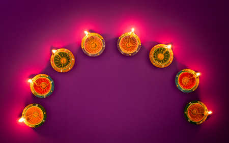 Happy Diwali - Clay Diya lamps lit during Dipavali, Hindu festival of lights celebration. Colorful traditional oil lamp diya on purple backgroundの写真素材