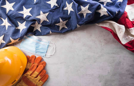 Happy Labor day concept during coronavirus disease (Covid-19). American flag with different construction tools and medical mask on dark stone background.の写真素材