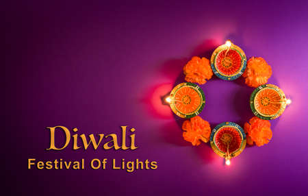 Happy Diwali - Clay Diya lamps lit during Dipavali, Hindu festival of lights celebration. Colorful traditional oil lamp diya on purple backgroundの写真素材