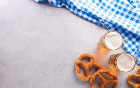 Oktoberfest festival decoration symbols made from Pretzel loaf, beer, sausage, potato chips and Bavarian white and blue fabric on stone background.の写真素材