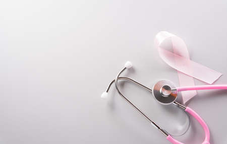 Pink ribbon and stethoscope on paper background for supporting breast cancer awareness month campaign.の写真素材
