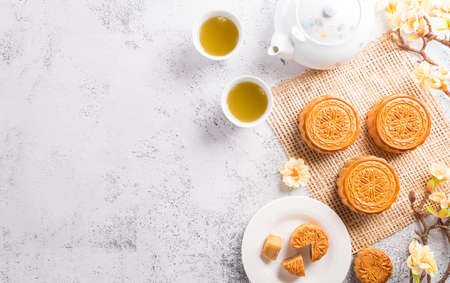 Chinese Mid-Autumn Festival concept made from mooncakes, tea and plum blossom on white stone background.の写真素材