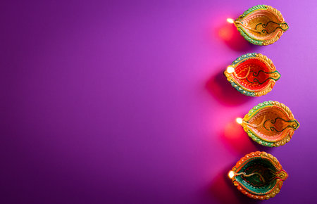 Happy Diwali - Clay Diya lamps lit during Dipavali, Hindu festival of lights celebration. Colorful traditional oil lamp diya on purple backgroundの写真素材