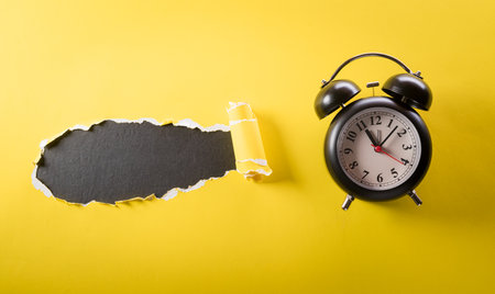 Top view of black alarm clock on yellow and black background. Shopping concept boxing day and Black Friday composition.の写真素材