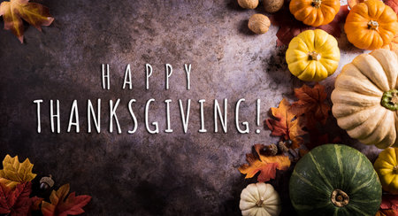 Thanksgiving background concept with fall leaves, pumpkin and seasonal autumnal decor and the text on dark stone background.の写真素材