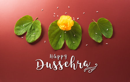 Happy Dussehra. Yellow flowers, green leaf and rice on dark paper background. Dussehra Indian Festival concept.の写真素材