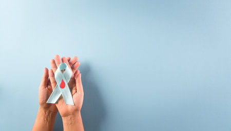 World diabetes day awareness concept. Hand holding blue ribbon, symbolic bow color raising awareness in diabetes day on pastel background,  14 November.の写真素材