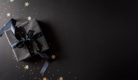 Top view of black Christmas gift boxes with black ribbon on black  background with copy space for text. Black Friday composition.の写真素材