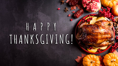 Thanksgiving dinner background concept with turkey roasted and all sides dishes, fall leaves, pumpkin and seasonal autumnal decor on dark stone background, top view, copy space.の写真素材