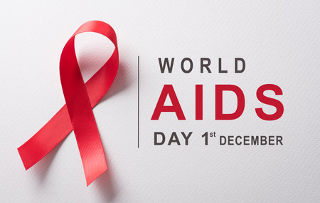 Closeup red ribbon HIV, world AIDS day awareness ribbon and the text on white background. Healthcare...