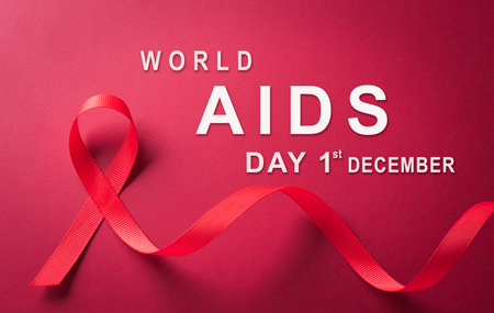 Closeup red ribbon HIV, world AIDS day awareness ribbon and the text on red background. Healthcare...