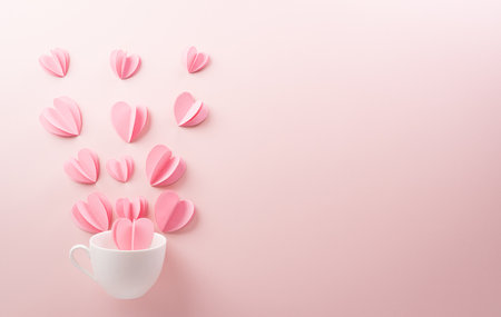 Pink paper hearts splash out from white coffee cup on pastel pink paper background. Love and Valentine's day concept.の写真素材