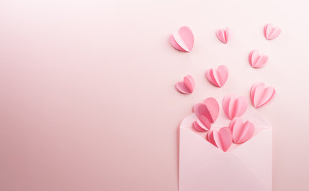 Pink paper hearts splash out on pastel pink paper background. Love and Valentine's day concept.の写真素材