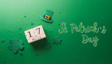 Happy St Patrick's Day decoration concept made from shamrocks ( clover leaf), wooden calendar and leprechaun hat on green background.の写真素材