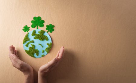 Hands holding paper earth with grass on brown background. World environment day, earth day and save earth concept.の写真素材