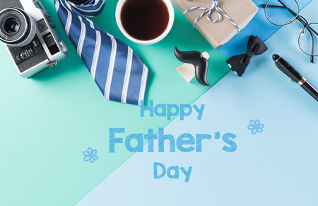 Happy Fathers Day background concept with coffee cup, decorated bow tie, necktie, eyeglasses, gift box and mustache on bright pastel background.の写真素材
