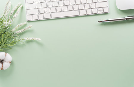 Flat lay, top view office table desk. Workspace with keyboard, office supplies and flower on pastel background.の写真素材