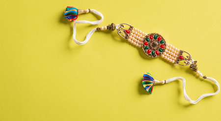 Raksha Bandhan, Indian festival with beautiful Rakhi and  Rice Grains on yellow background.  A traditional Indian wrist band which is a symbol of love between Sisters and Brothers.の写真素材