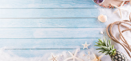 Summer holiday, travel and vacation concept. Beach hat with sunglasses, starfish, rope, pineapple and sea shell on pastel blue wooden background.の写真素材