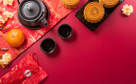 Chinese Mid-Autumn Festival concept made from mooncakes, tea and plum blossom on red background.の写真素材
