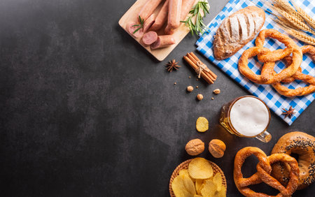 festival decoration symbols made from Pretzel loaf, beer, and Bavarian white and blue fabric on dark stone background.の写真素材
