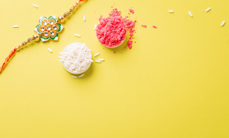 Raksha Bandhan, Indian festival with beautiful Rakhi and Rice Grains on yellow background. A traditional Indian wrist band which is a symbol of love between Sisters and Brothersの写真素材