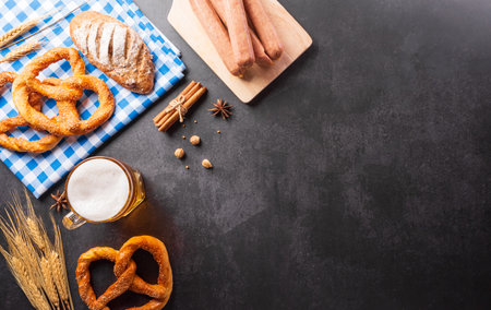 festival decoration symbols made from Pretzel loaf, beer, sausage, potato chips and Bavarian white and blue fabric on dark stone background.の写真素材