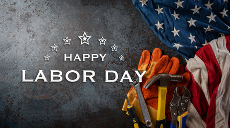 Happy Labor day concept. American flag with different construction tools and the text on dark stone background.の写真素材