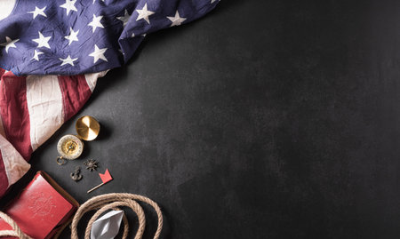 Happy Columbus Day concept. Vintage American flag, compass, paper boat, rope on dark stone background.  Flat lay, top view with copy space.の写真素材