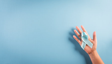 World diabetes day awareness concept. Hand holding blue ribbon, symbolic bow color raising awareness in diabetes day on pastel background,  14 November.の写真素材