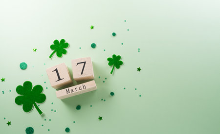 Happy St Patrick's Day decoration concept made from shamrocks ( clover leaf) and wooden calendar on green pastel background.の写真素材