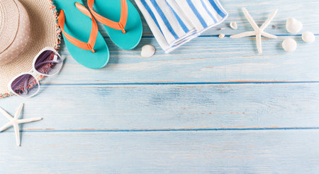 Summer holiday, travel and vacation concept. Sunglasses, starfish, beach hat, flip flop and sea shell on pastel blue wooden background.の写真素材