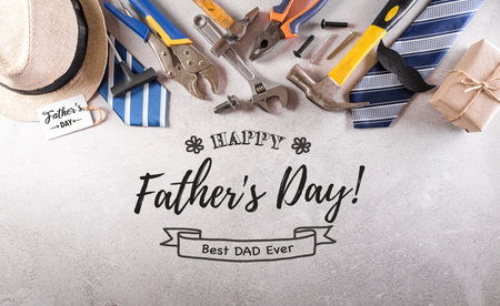 Happy Father's Day decoration with beautiful tie with mustache, hand tools, glasses, gift box and hat on dark stone background.の写真素材