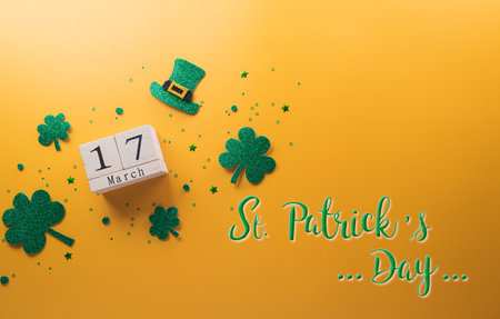 Happy St Patrick's Day decoration concept made from shamrocks ( clover leaf), wooden calendar and leprechaun hat on yellow background.の写真素材