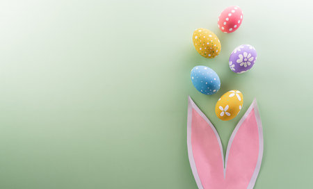 Easter party concept. Top view of easter bunny ears and colorful eggs on pastel background with copy space for the text.の写真素材