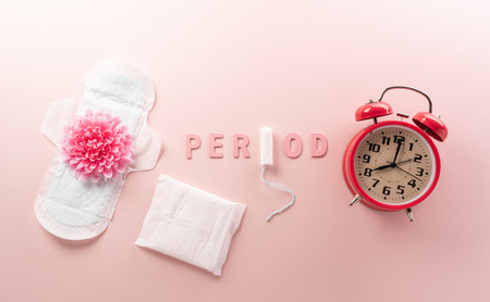 White sanitary pad and a clock on pastel background. Woman health or body positive concept.の写真素材