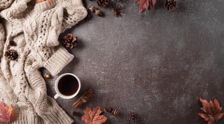 Autumn composition. A cup of coffee, cotton flowers, autumn leaves and sweater on dark stone...