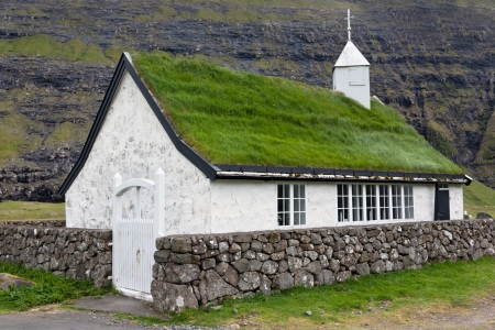 Small church surrounded by high mountains in the village of Saksun, Faroe Islands .の写真素材