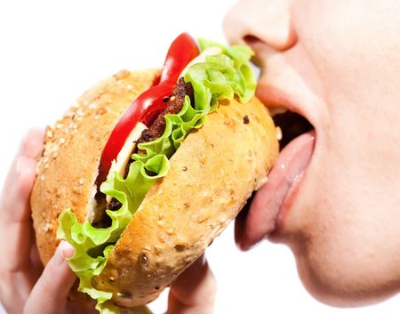Young woman eating colorful appetizing hamburgerの写真素材