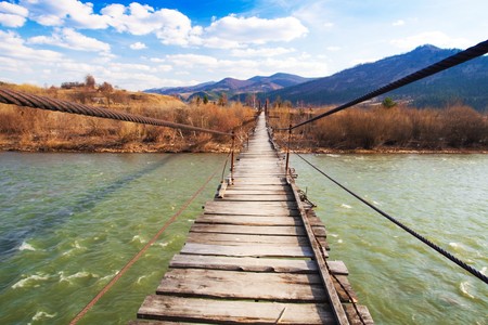 Suspended wooden bridge over a riverの写真素材