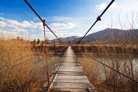 Suspended wooden bridge over a riverの写真素材