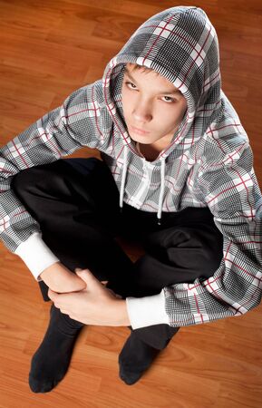 attractive teen boy sitting on the wooden floorの写真素材
