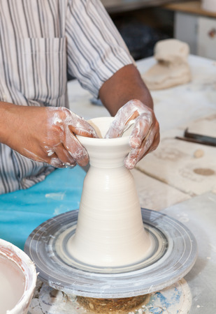 Hands working on pottery wheel , close up retro style toned photo wit shallow DOFの写真素材