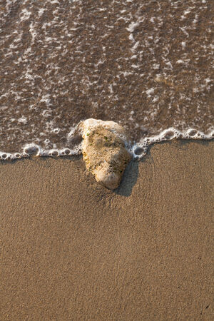 Sea waves lash line impact rock on the beachの写真素材