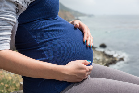 Outdoor shot of pregnant woman with her hands on the bellyの写真素材