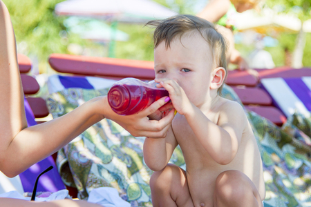 baby drinking water on the beachの写真素材