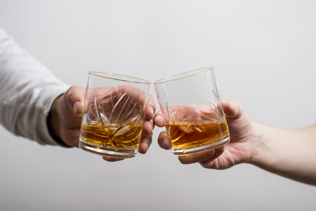 Two men clanging glasses of alcoholic beverage together whileの写真素材